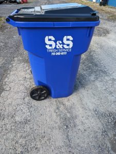 Picture of a blue garbage toter with the label S&S Trash Service printed on the side in white font.